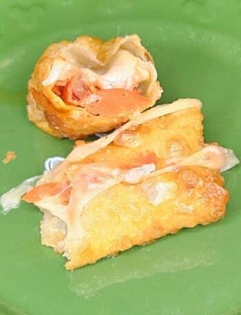 Disney Pepperoni Spring Rolls Recipe: one spring roll cut in half showing the pepperoni and mozzarella cheese on the inside.