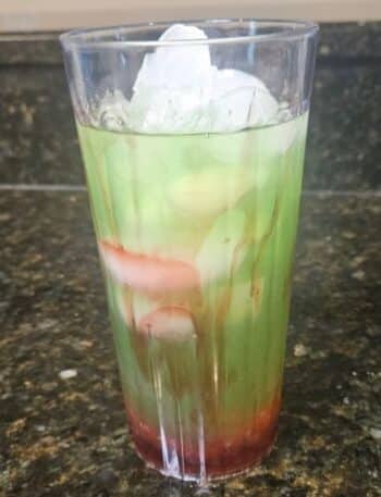 Green Apple Spell Lemonade Recipe: A clear cup filled with cherry popping boba, raspberry sauce, and a green lemonade.