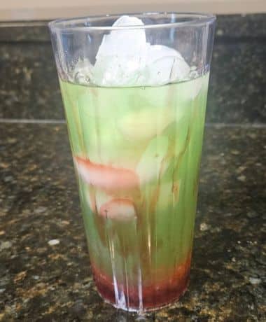 Green Apple Spell Lemonade Recipe: A clear cup filled with cherry popping boba, raspberry sauce, and a green lemonade.