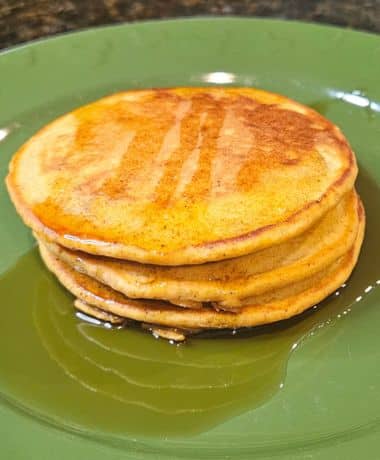 Kona Café Pumpkin Pancakes Recipe: 3 pancakes topped with maple syrup on a green plate with Mickey Mouse icons.