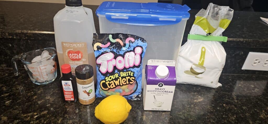 Oogie Boogie Slushy Recipe Ingredients: Ice, Apple Cider, Vanilla Extract, Cinnamon, Sugar, Sour Gummy Worms, Lemon, Heavy Whipping Cream, Powdered Sugar